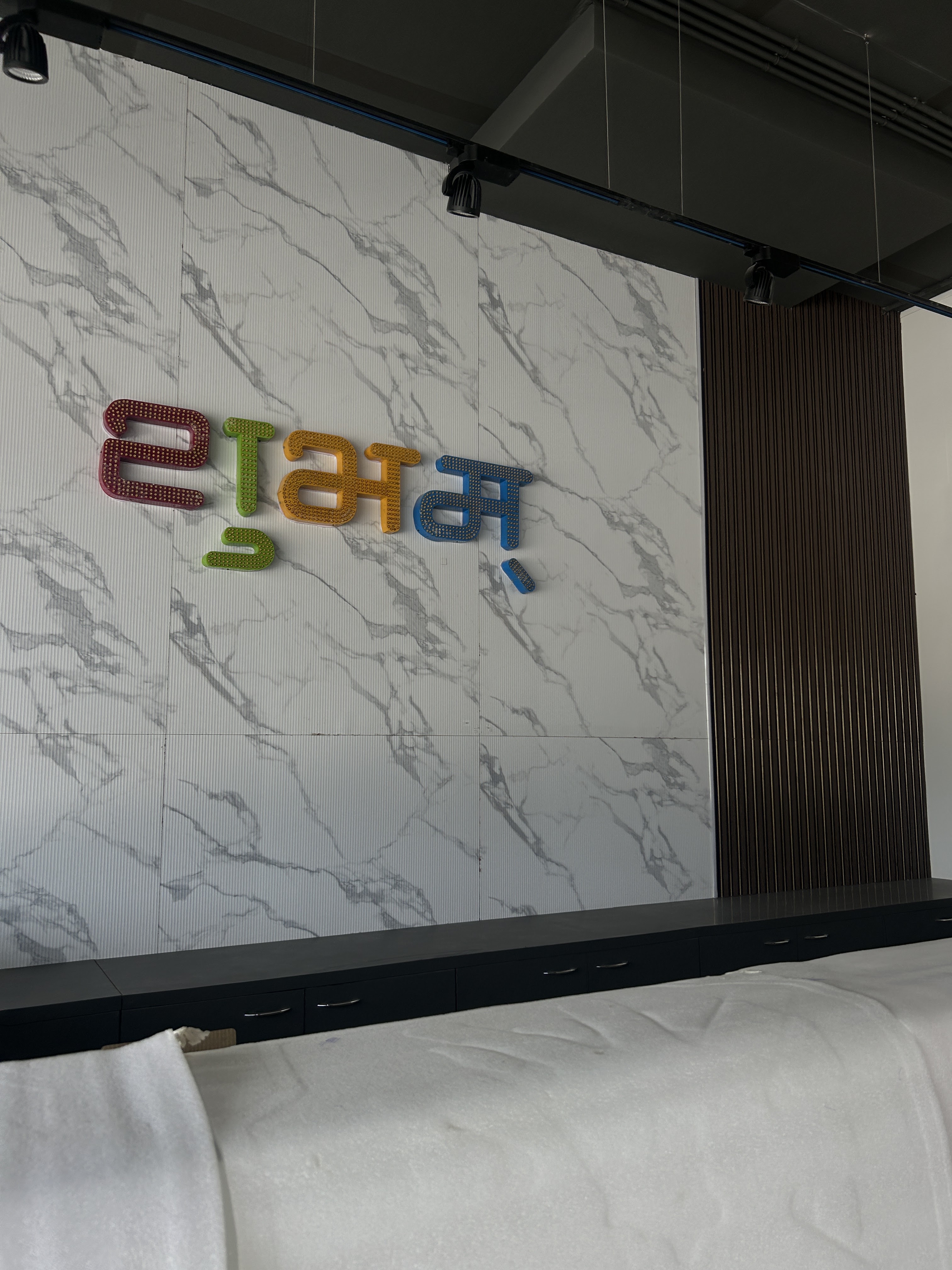 Interior of Shubham Fashion store showing the 3D शुभम् (Shubham) wall-mounted letters in brand colors on a marble wall